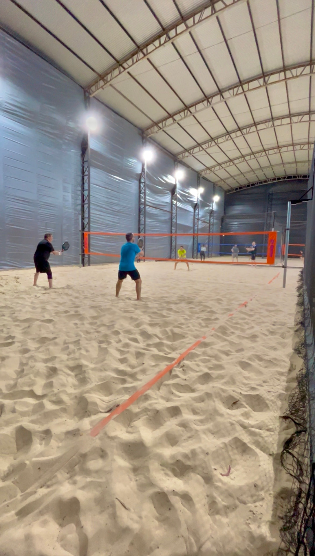 Partida de beach tennis na areia sob as árvores
